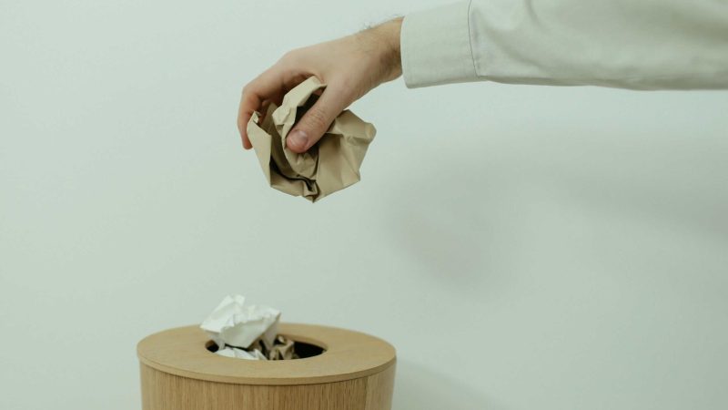 Person discarding paper into a wooden shredder bin in South Africa.