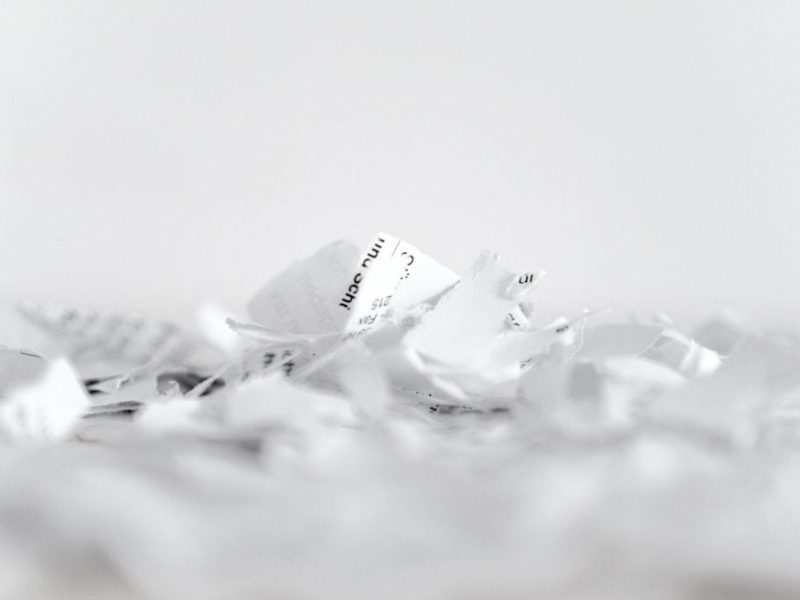 Crumpled paper with shredded paper pieces on white background.